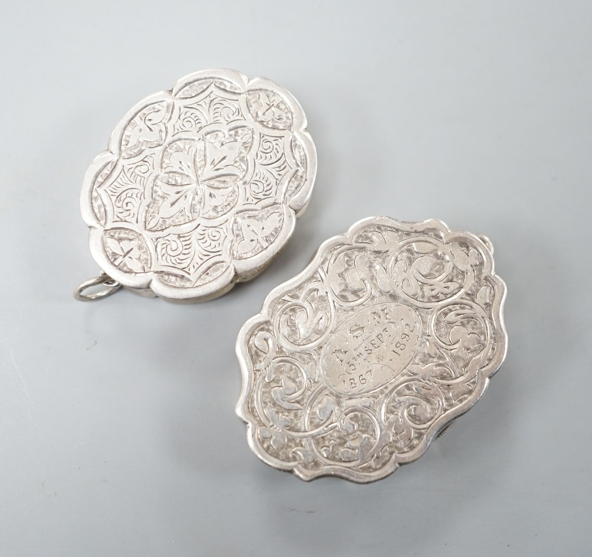 A Victorian engraved silver cusped oval vinaigrette, Hilliard & Thomasson, Birmingham, 1882, 39mm and a larger vinaigrette by George Unite, with engraved inscription.
